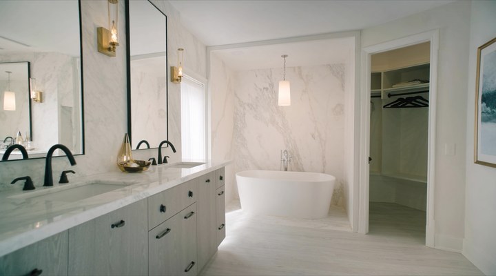 Elegant bathroom featuring a dual vanity set against a marbled wall, with a spacious walk-in closet, ideal for bathroom remodeling projects.