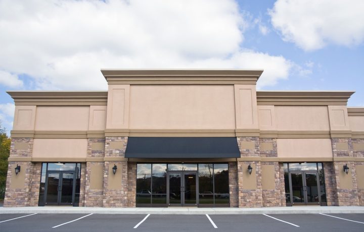 Single-story commercial building with stone facade, black awnings and striped parking lot — example of commercial construction work by Ponderosa Builders LLC