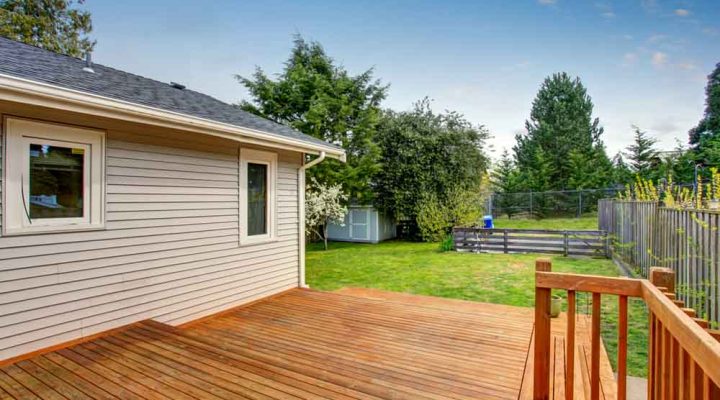A straightforward wooden deck overlooking a well-maintained garden, suitable for outdoor activities and family gatherings.