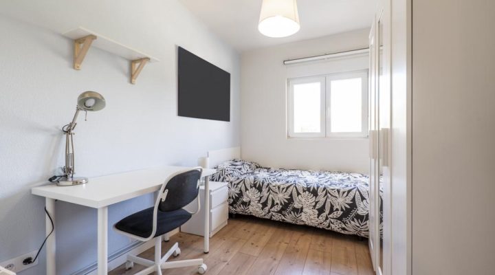 Compact bedroom with a simple desk, chair, and bed, designed for efficient use of space, perfect for small bedroom layouts.
