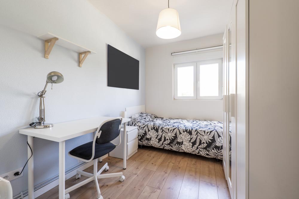 Compact bedroom with a simple desk, chair, and bed, designed for efficient use of space, perfect for small bedroom layouts.