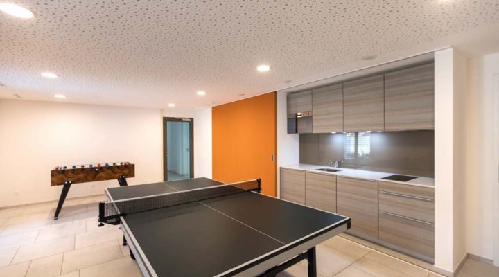 A versatile game room equipped with a ping pong table, foosball, and a modern kitchenette, designed for entertainment and leisure activities.