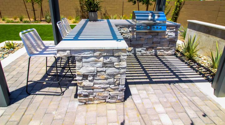 A modern outdoor kitchen featuring stone countertops and a built-in barbecue, ideal for enhancing outdoor spaces with stone construction.