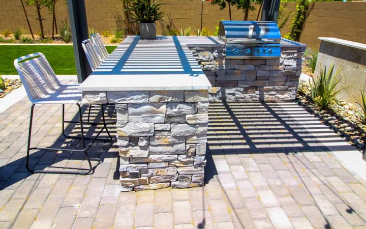 A modern outdoor kitchen featuring stone countertops and a built-in barbecue, ideal for enhancing outdoor spaces with stone construction.