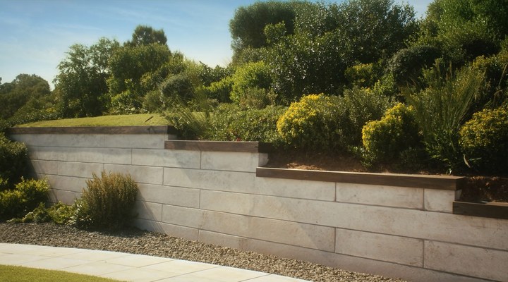 A meticulously constructed grey concrete retaining wall in a residential garden, showcasing precise work in concrete construction.