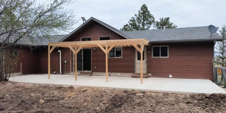 A residential home featuring a covered deck with natural wood columns, reflecting Ponderosa Builders LLC’s expertise in deck and pergola construction.