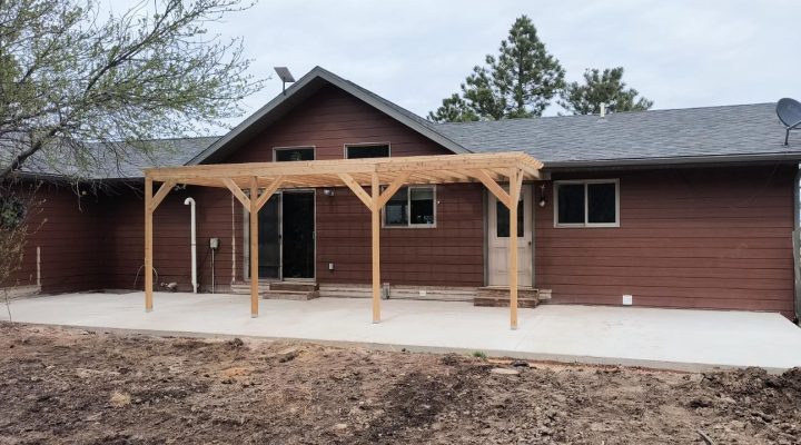 A residential home featuring a covered deck with natural wood columns, reflecting Ponderosa Builders LLC’s expertise in deck and pergola construction.