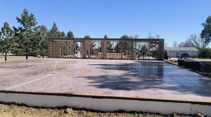 Early stages of residential home construction showing a large concrete foundation, underlining Ponderosa Builders LLC's concrete services.