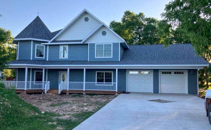 A stunning home with a large front porch and two-car garage, highlighting the custom home construction and addition services offered by Ponderosa Builders LLC.