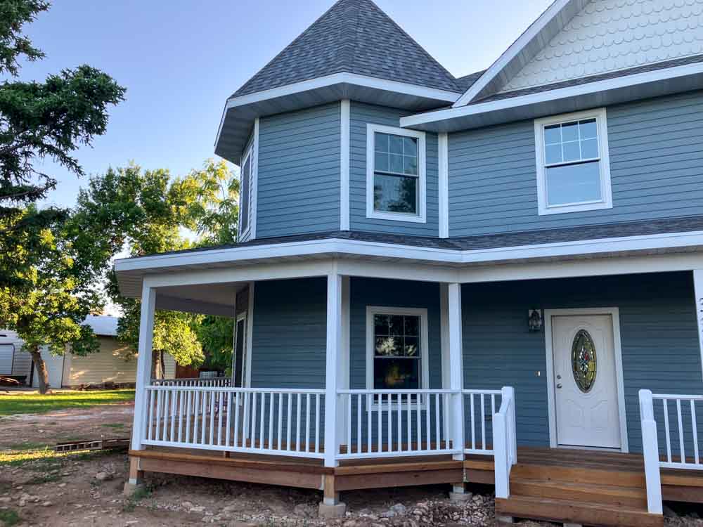 An elegant two-story home featuring a spacious front porch, showcasing the comprehensive home remodeling and addition services by Ponderosa Builders LLC.