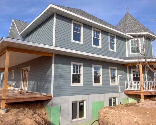 A two-story home under construction with modern design and grey siding, emphasizing the expertise in home additions and remodeling by Ponderosa Builders LLC.