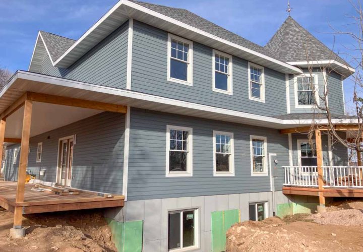 A two-story home under construction with modern design and grey siding, emphasizing the expertise in home additions and remodeling by Ponderosa Builders LLC.