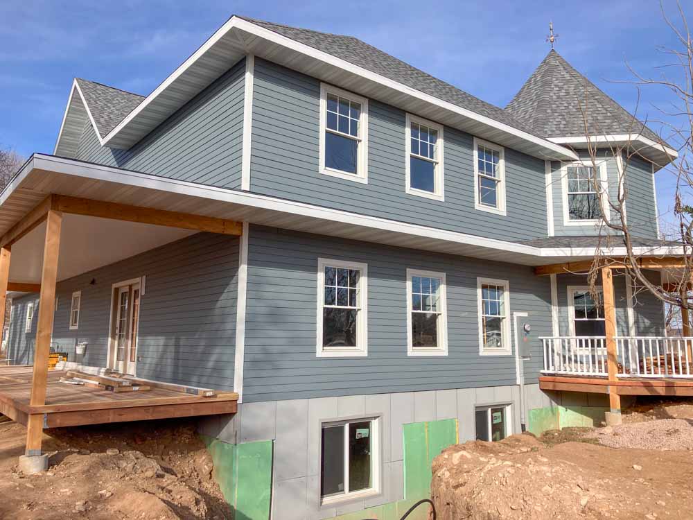 A two-story home under construction with modern design and grey siding, emphasizing the expertise in home additions and remodeling by Ponderosa Builders LLC.