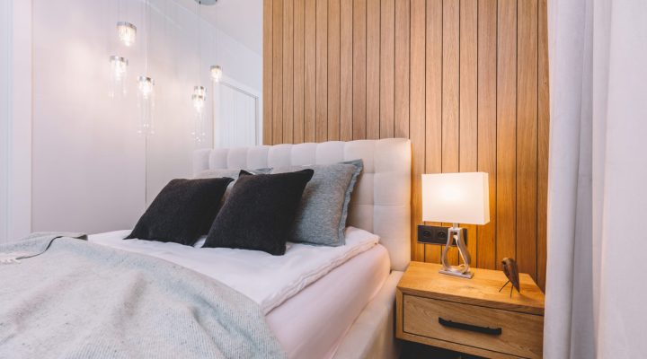 Intimate bedroom with wooden wall paneling and pendant lights, offering a warm and inviting atmosphere, suitable for modern bedroom designs.